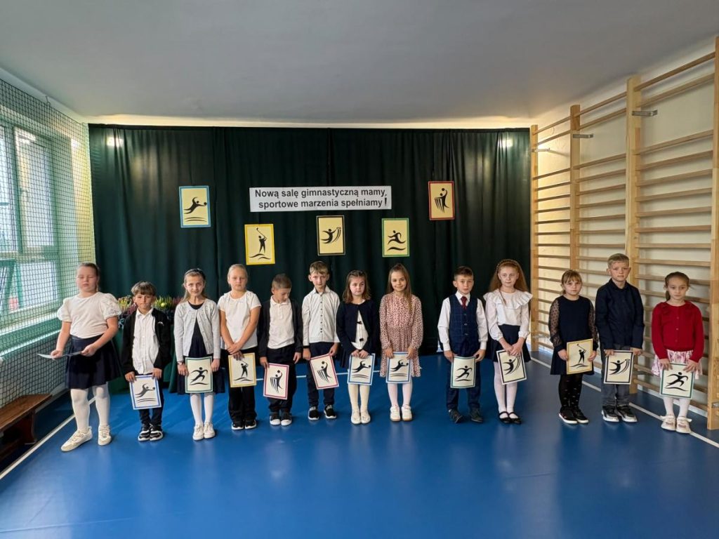 Uczniowie Szkoły Podstawowej w Brzeznej-Litaczu w odnowionej sali gimnastycznej z drabinkami i napisem „Nową salę gimnastyczną mamy, sportowe marzenia spełniamy!”