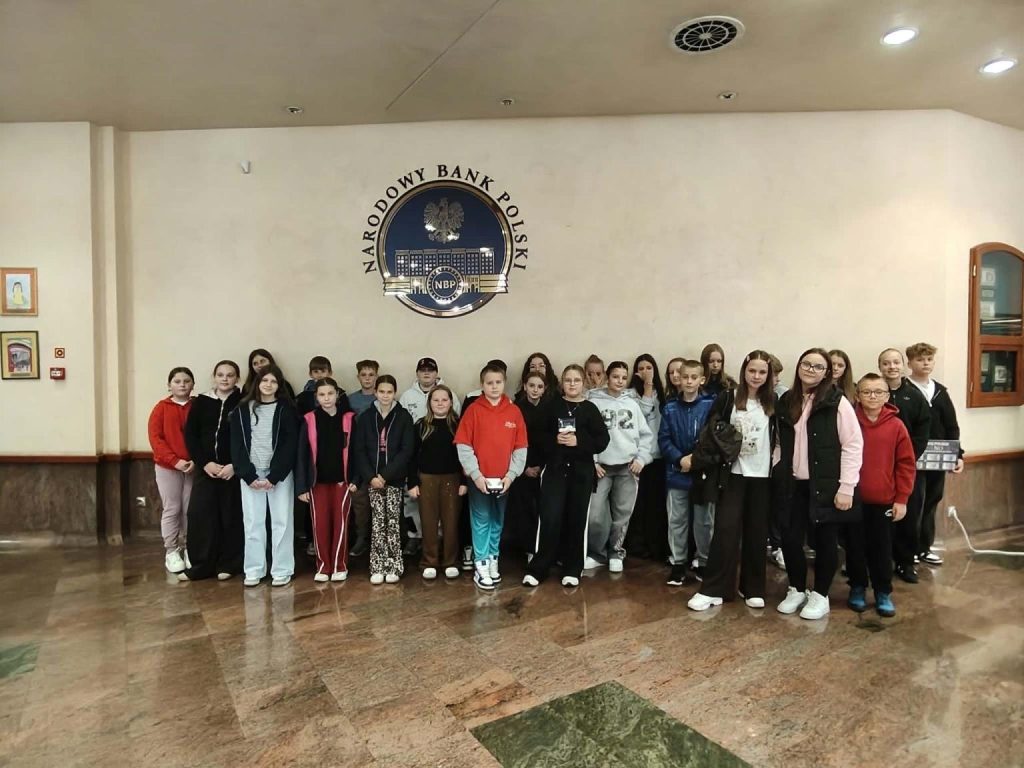 Grupa uczniów SP w Długołęce-Świerkli w holu Narodowego Banku Polskiego we Wrocławiu, pod godłem NBP