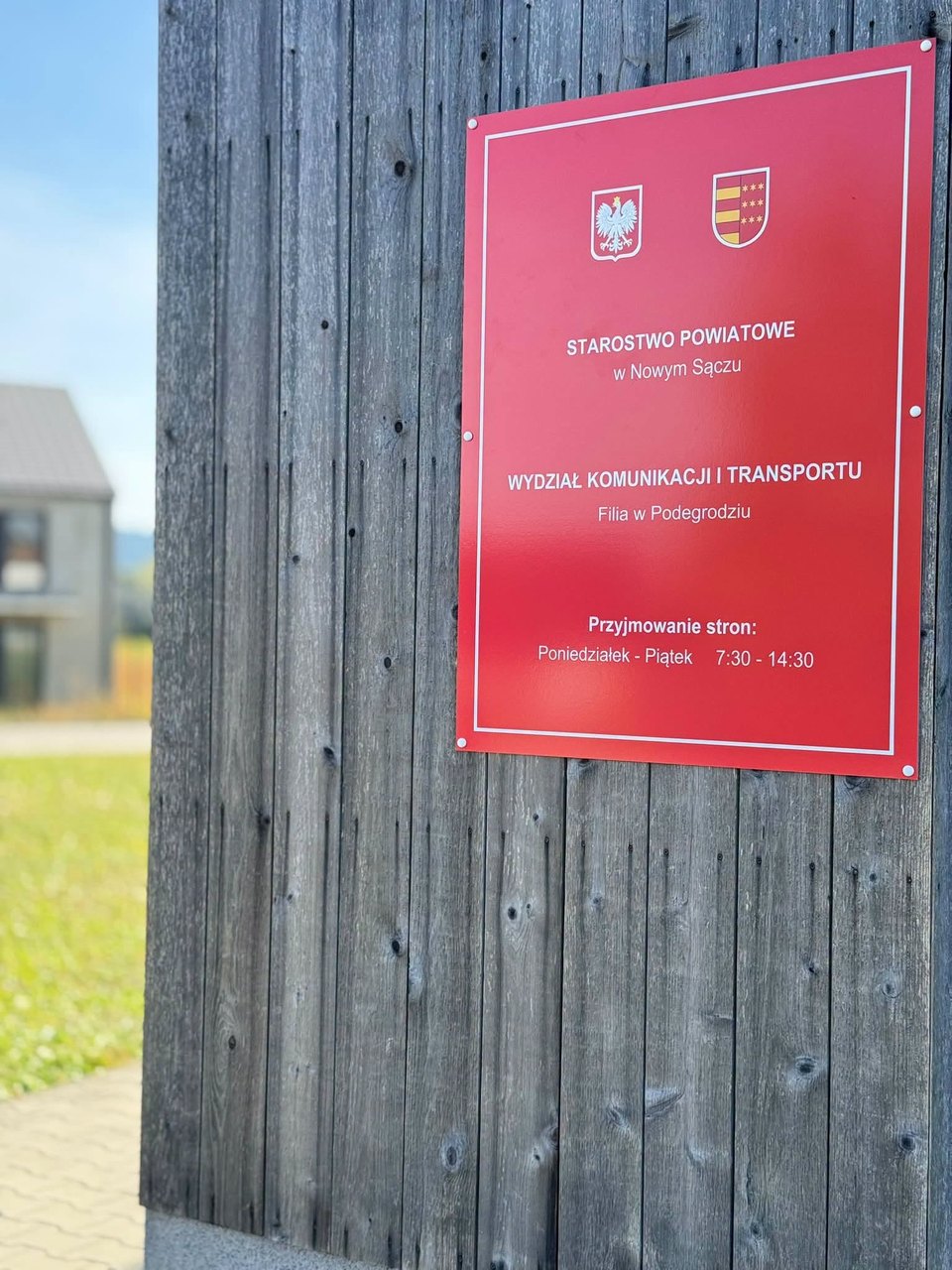 Tablica filii Wydziału Komunikacji i Transportu Starostwa Powiatowego w Nowym Sączu w Podegrodziu – przyjmowanie stron od poniedziałku do piątku w godz. 7:30–14:30
