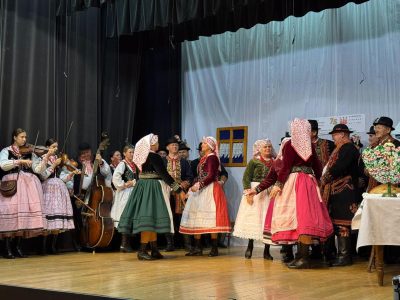 Regionalny Zespół Podegrodzie w strojach lachowskich na scenie GOK w Podegrodziu – tancerki i muzycy ze skrzypcami i basem